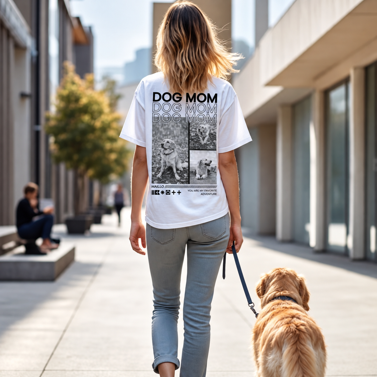 T-shirt bianca con la scritta "DOG MOM" e foto di cani sul retro, indossata da una donna con un cane.