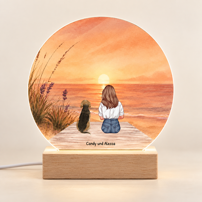 Luce notturna LED personalizzata con tramonto colorato, base in legno, motivo di donna e cane.