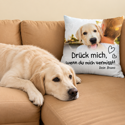 Cuscino beige con scritta e motivo di cane, su un divano accanto a un labrador.