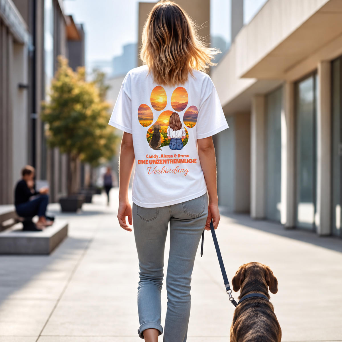 T-shirt bianca con design personalizzato e frase, vista posteriore di una donna che porta a spasso un cane.