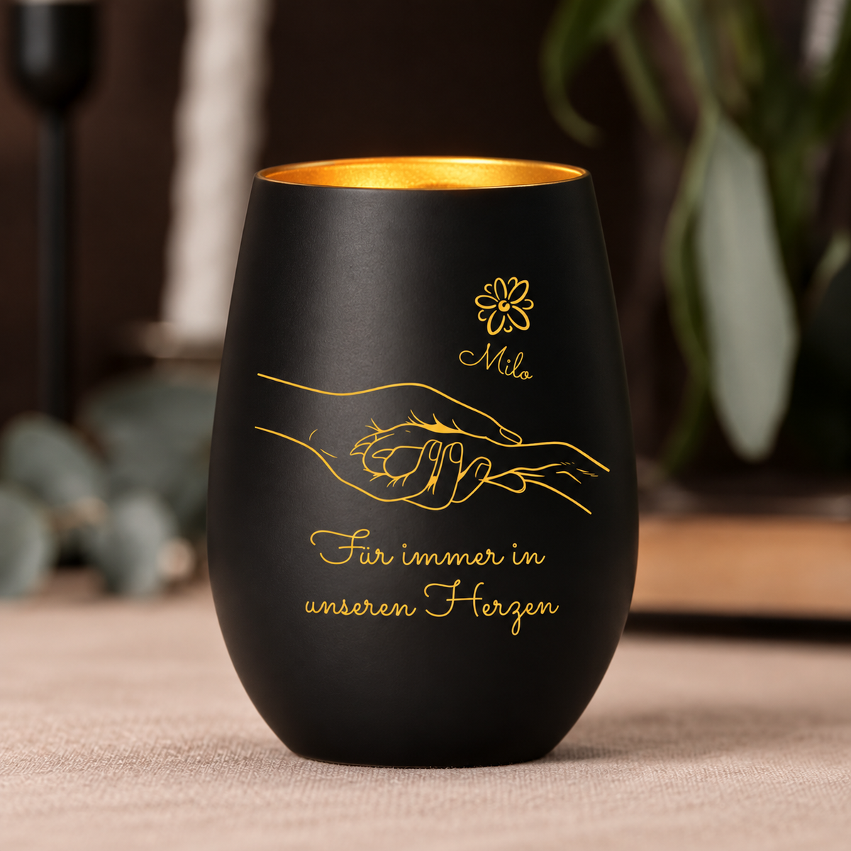 Lumino commemorativo nero con interno dorato, personalizzato con design di mani e il testo "Für immer in unseren Herzen".