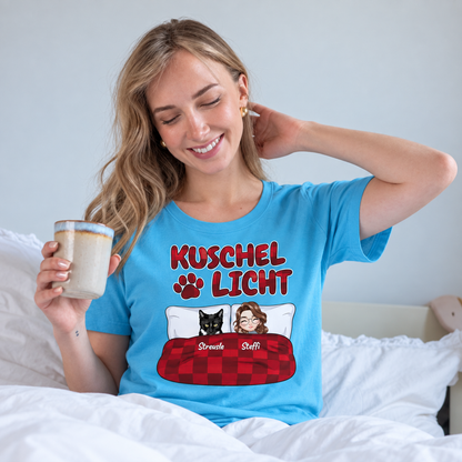 T-shirt turchese con la scritta "Kuschel Licht", indossata da una donna sorridente a letto.