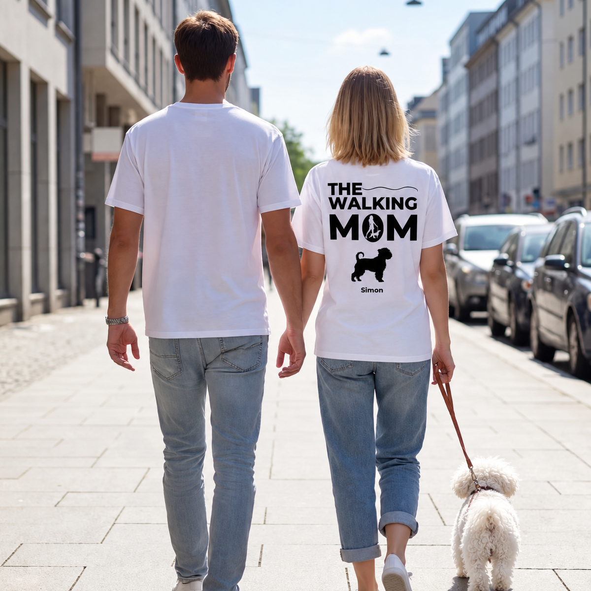 Due persone con T-shirt bianche con la scritta "THE WALKING MOM" e un cane, per strada.