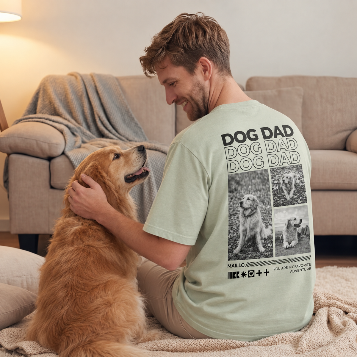 T-shirt verde chiaro con la scritta "Dog Dad" e motivi di cani, indossata da un uomo seduto a terra.