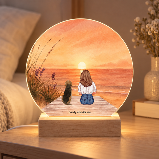 Luce notturna LED personalizzata con illustrazione di una donna e il suo cane in spiaggia al tramonto. Base in legno.