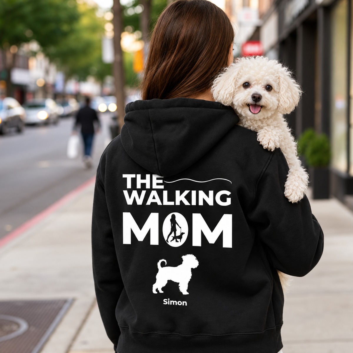 Felpa con cappuccio nera con stampa personalizzata "THE WALKING MOM" e motivo di cane. Persona con un cane in braccio.