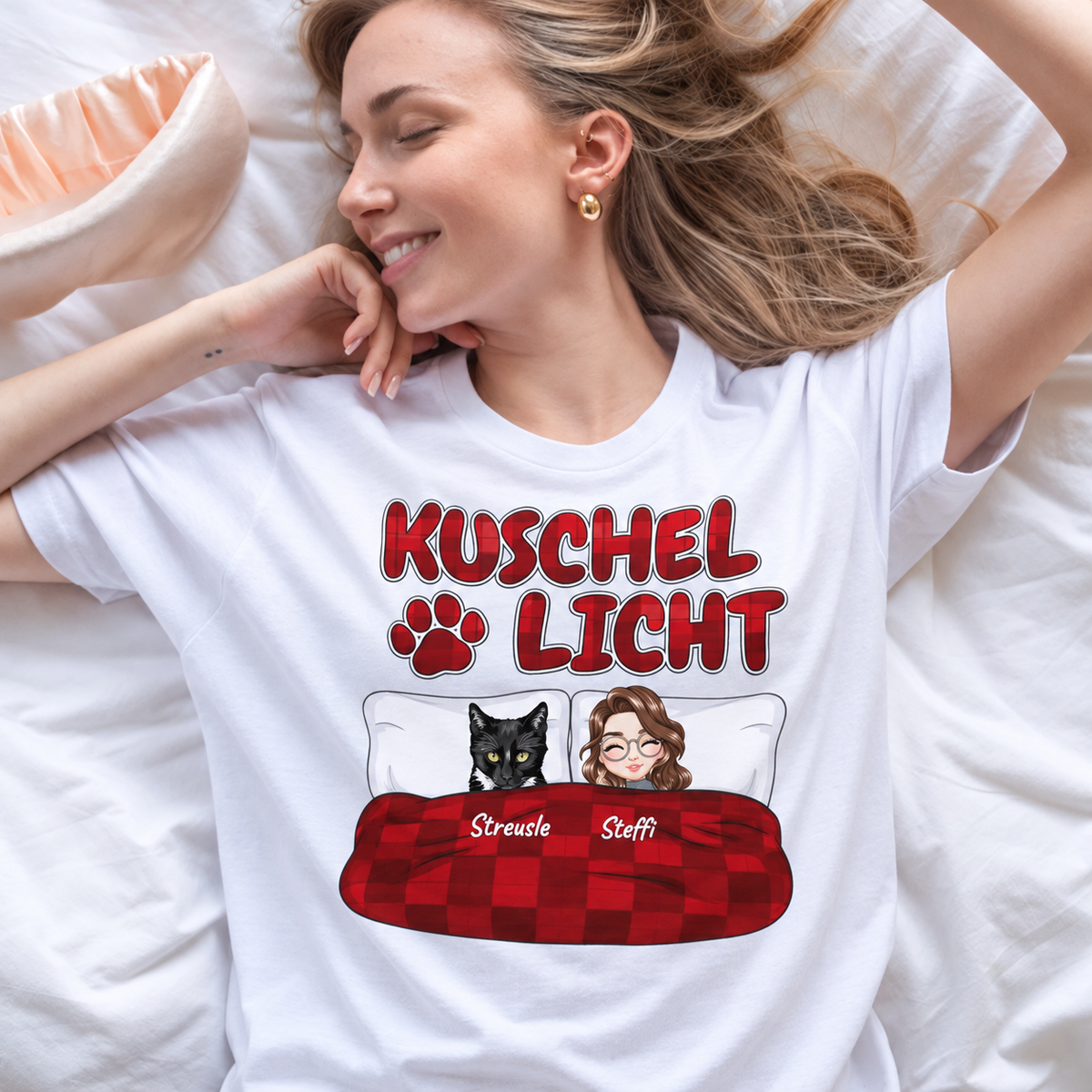 T-shirt bianca con la scritta "Kuschel Licht" e il disegno di una donna e un gatto a letto.