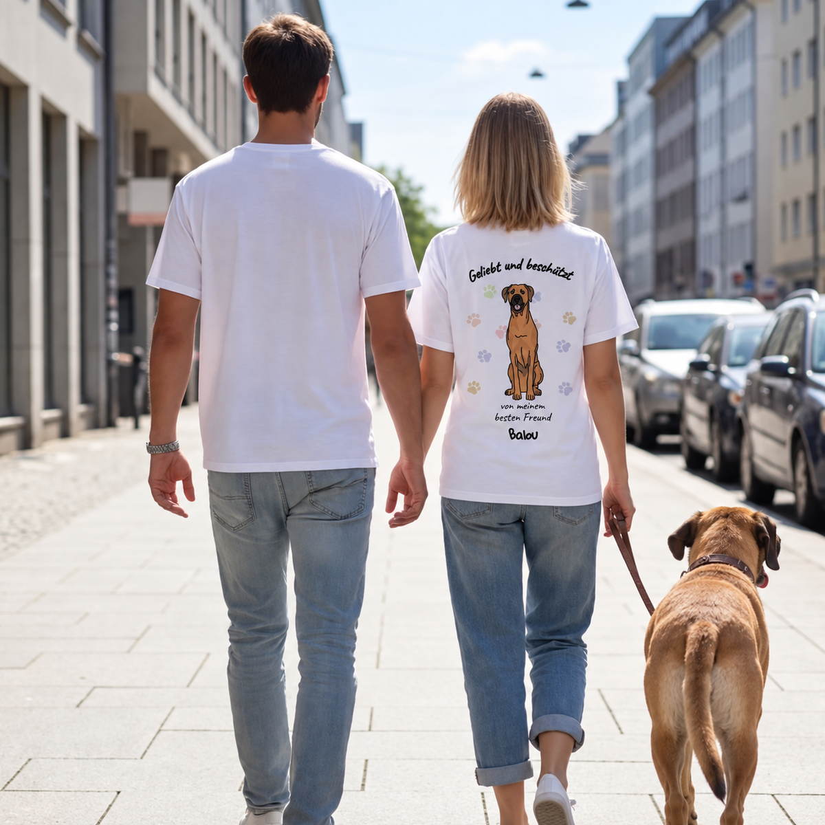 Due persone con T-shirt bianche con motivo di cane sul retro, a passeggio con un cane.
