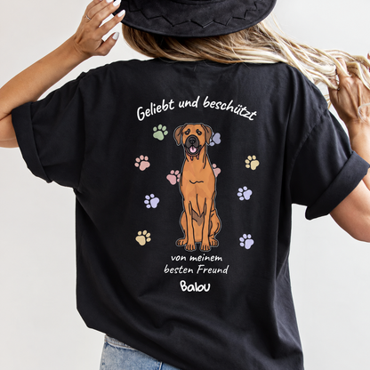 T-shirt nera con illustrazione di cane e la scritta "Geliebt und beschützt" sul retro.