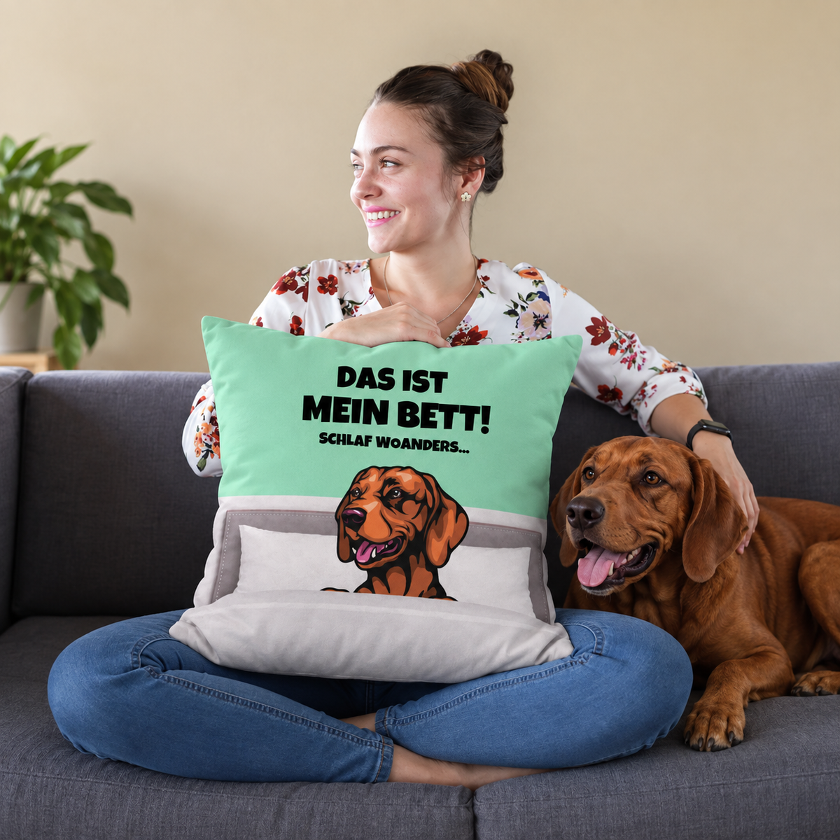 Cuscino personalizzato con motivo di cane e testo verde menta e grigio, su un divano con una donna e un cane.