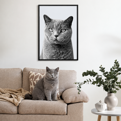 Ritratto grigio di animale incorniciato sopra un divano beige con un gatto grigio simile davanti.
