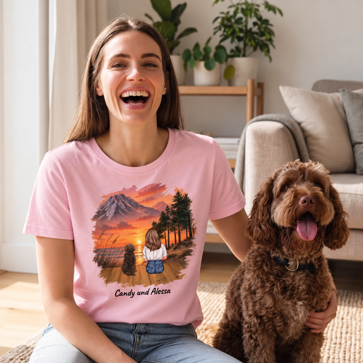 T-shirt rosa con stampa personalizzata di una donna e due cani davanti a un paesaggio al tramonto.