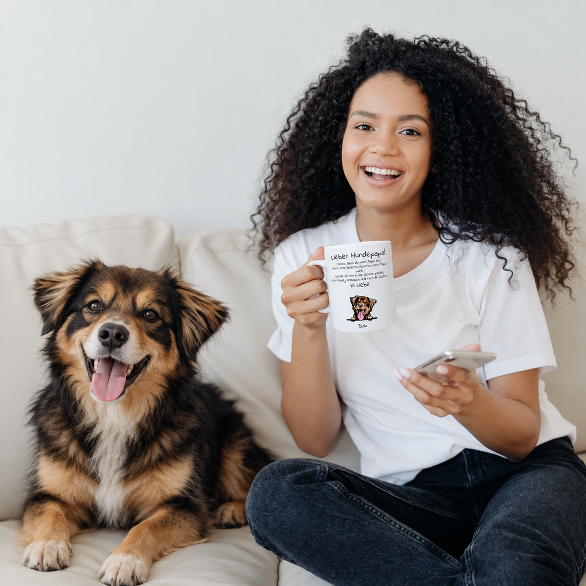 Donna con tazza personalizzata "Lieber Hundepapa" seduta accanto a un cane su un divano. La tazza mostra foto e testo.