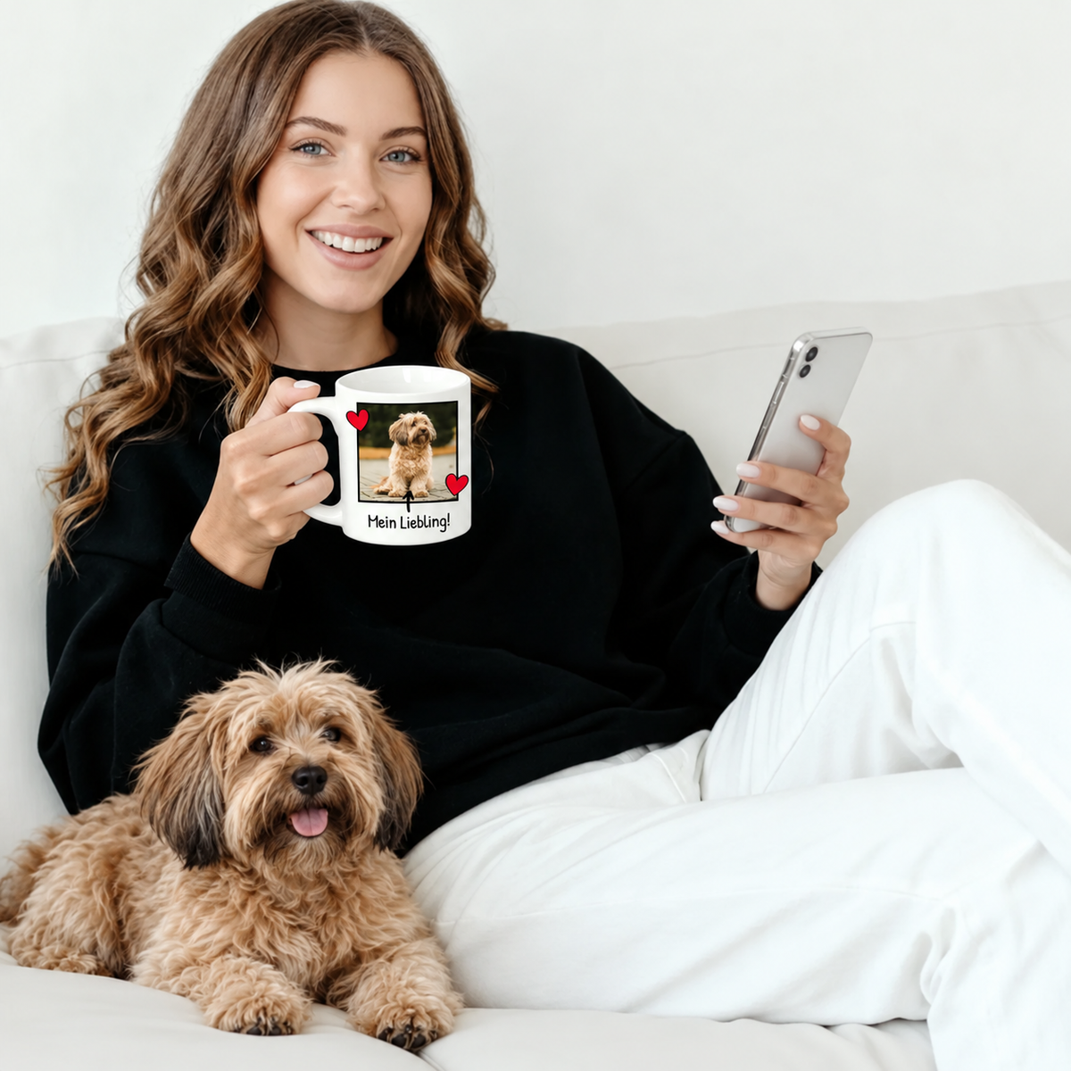 Donna con maglione nero con tazza personalizzata con foto e cane, seduta su un divano.
