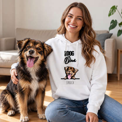 Persona sorridente con felpa bianca e un cane su un pavimento in legno, ambiente accogliente. La felpa mostra un cane.
