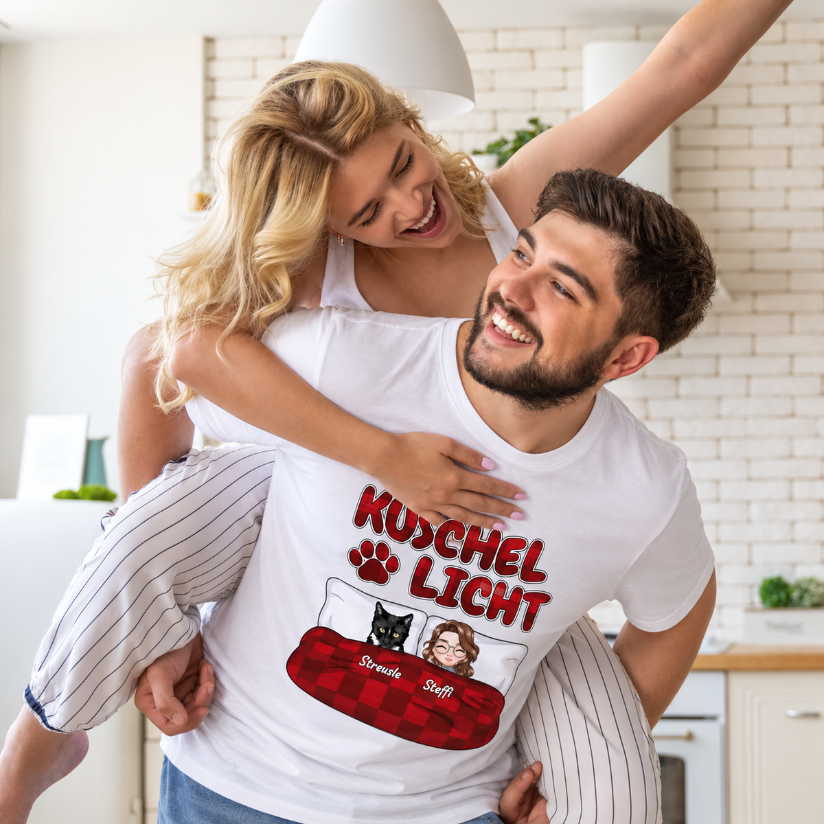 T-shirt bianca con la scritta "Kuschel Licht" e personaggi cartoon di una coppia e un gatto.