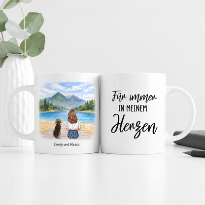Tazza bianca personalizzata con illustrazione di una donna e un cane al lago e il testo "Für immer in meinem Herzen".