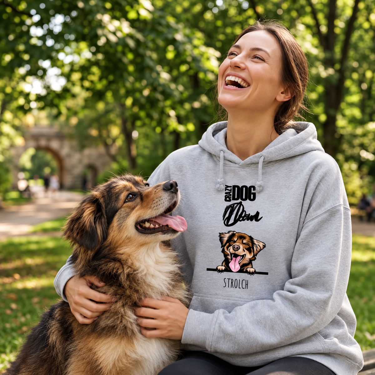 Felpa con cappuccio grigia con motivo di cane, indossata da una donna che ride e gioca con il suo cane al parco.