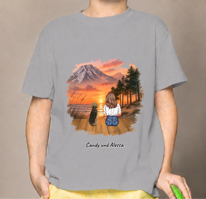 T-shirt per bambini grigia con grafica di una persona seduta e un cane al tramonto.