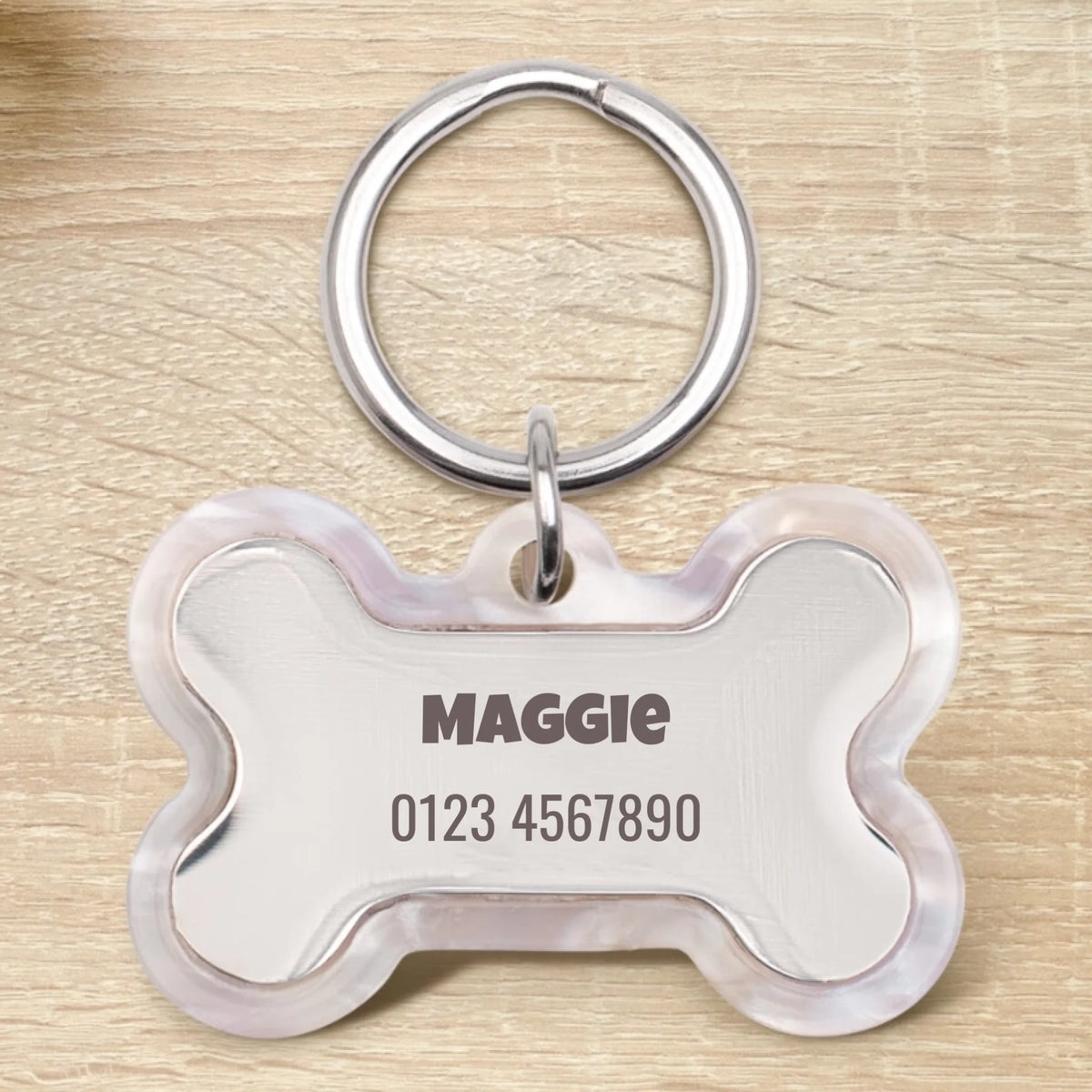 Medaglietta per cane in resina personalizzata a forma di osso con il nome Maggie e un numero di telefono.
