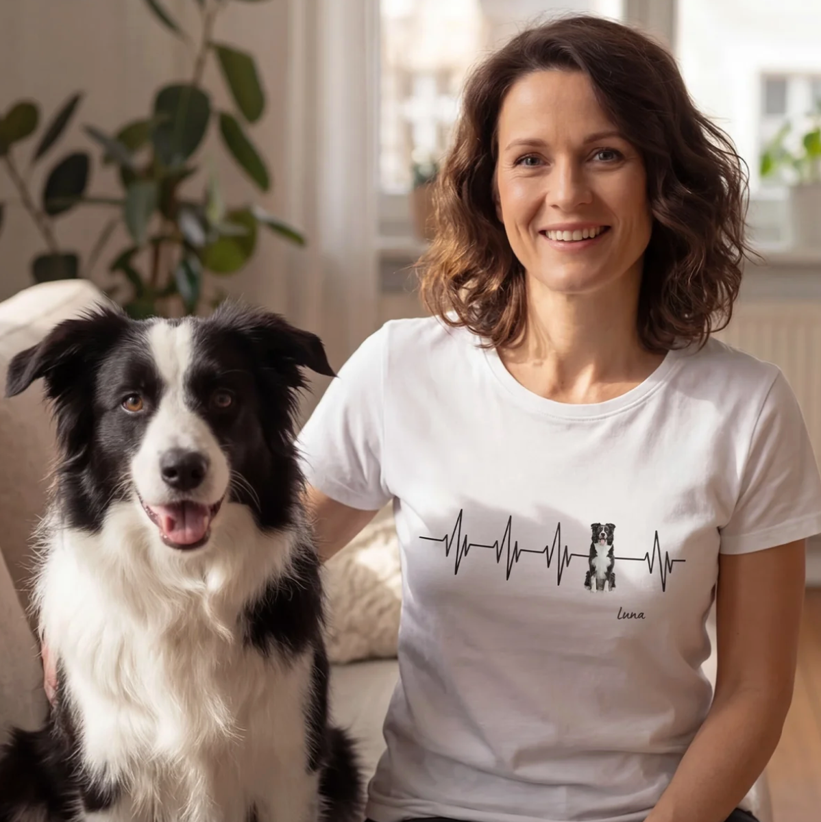 T-shirt bianca con design battito cardiaco e motivo di cane, personalizzabile. Donna seduta su un divano con un cane.
