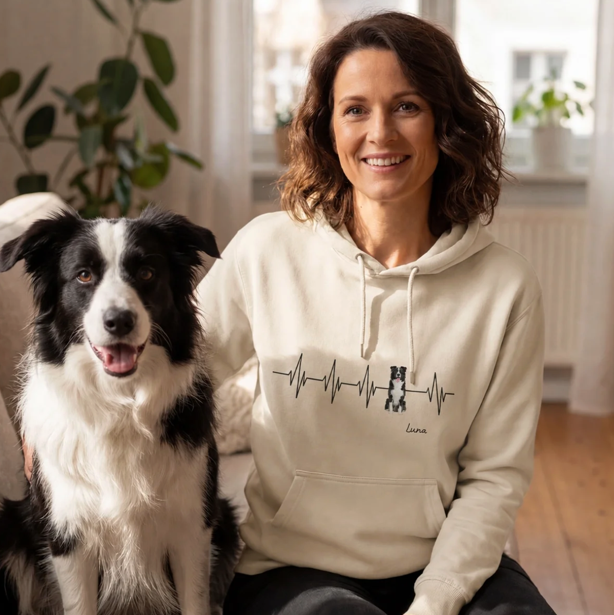 Felpa con cappuccio beige con motivo battito cardiaco e scritta personalizzata, indossata da una donna accanto a un cane.