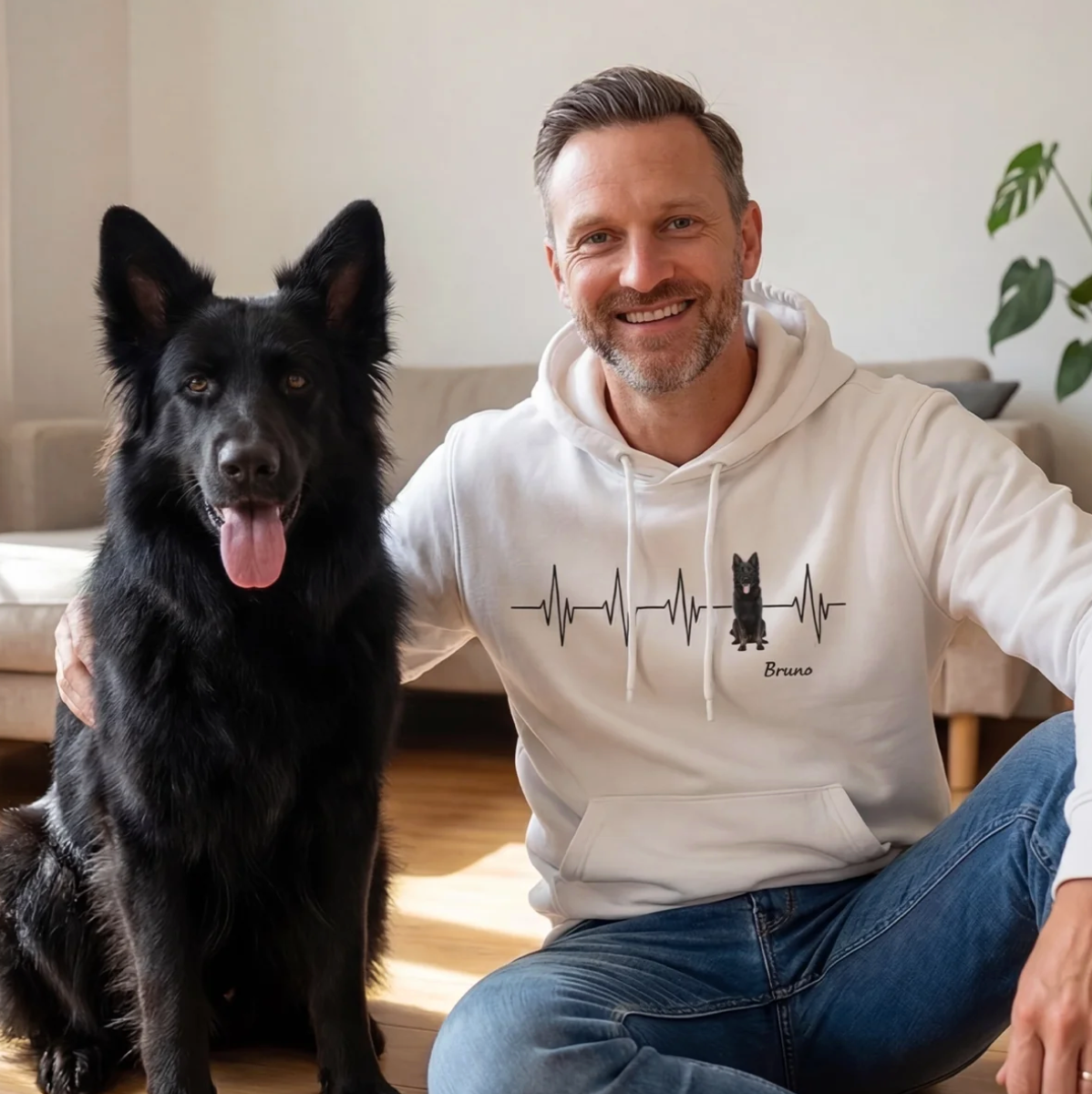 Felpa con cappuccio bianca con motivo battito cardiaco e cane, uomo seduto accanto a un cane nero.
