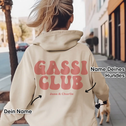 Felpa con cappuccio beige con la scritta rossa "GASSI CLUB" e nomi personalizzati. Persona che porta a spasso un cane.