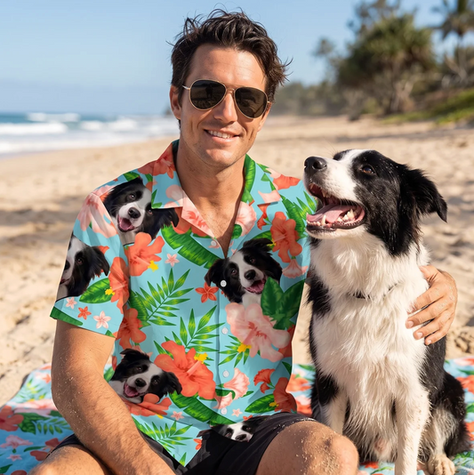Uomo con occhiali da sole e camicia hawaiana personalizzata con motivi di cani, seduto in spiaggia accanto a un cane.