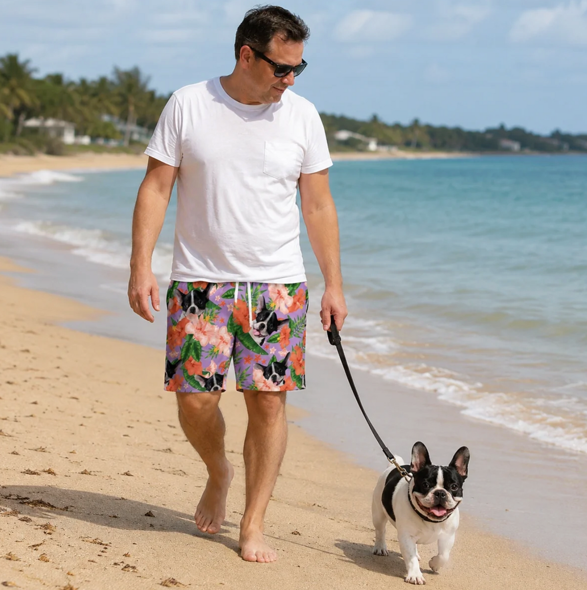Uomo con costume personalizzato a fantasia colorata di fiori e animali, cammina scalzo sulla spiaggia.