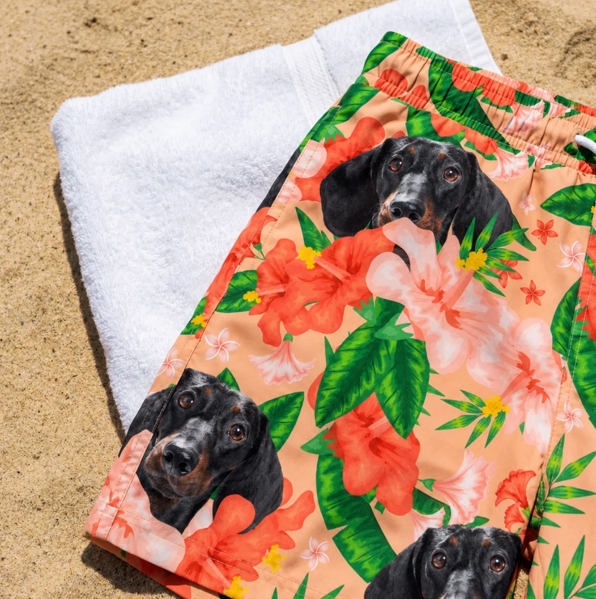 Costume da bagno personalizzato con motivi floreali e stampa di cane su una spiaggia di sabbia.