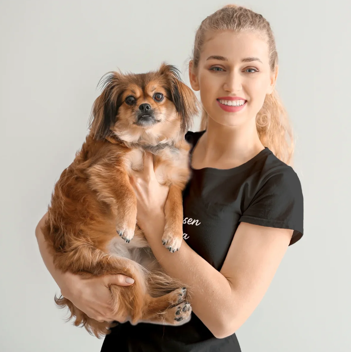 Donna che tiene in braccio un cagnolino, con una T-shirt nera personalizzata.