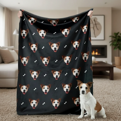 Coperta personalizzata con teste di animali su sfondo nero, tenuta da una persona con un cane in primo piano.