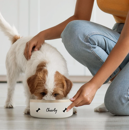 Cane che mangia da una ciotola bianca personalizzata con il nome "Charly" e motivi a ossa.