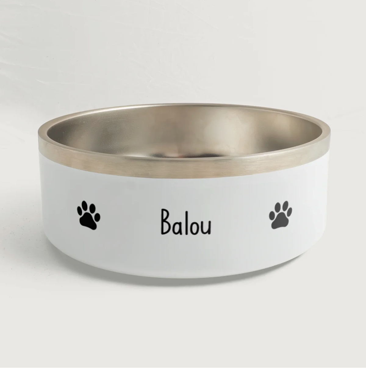 Ciotola personalizzata con bordo argentato, il nome "Balou" e impronte di zampe nere.