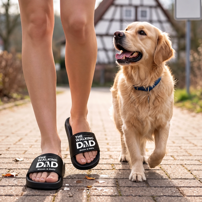 Ciabatte nere con stampa "THE WALKING DAD", indossate durante una passeggiata con un golden retriever.