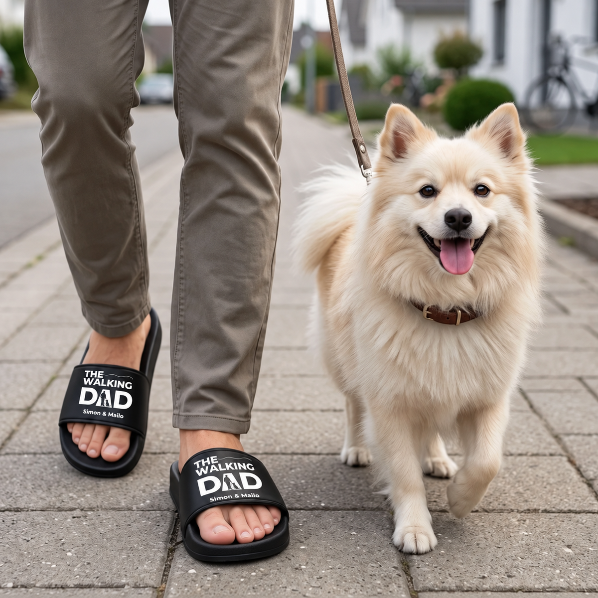 Persona che indossa ciabatte nere personalizzate con la stampa "THE WALKING DAD" mentre porta a spasso un cane.