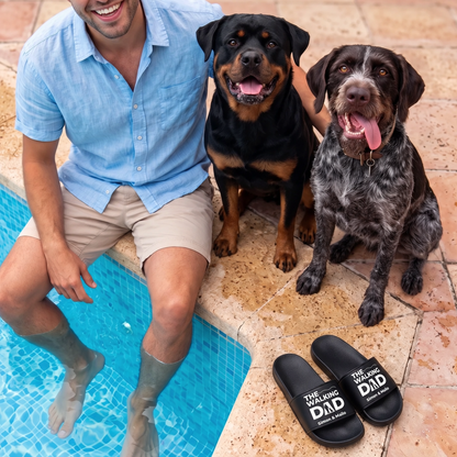 Ciabatte nere personalizzate con stampa "THE WALKING DAD", accanto a un uomo e due cani a bordo piscina.
